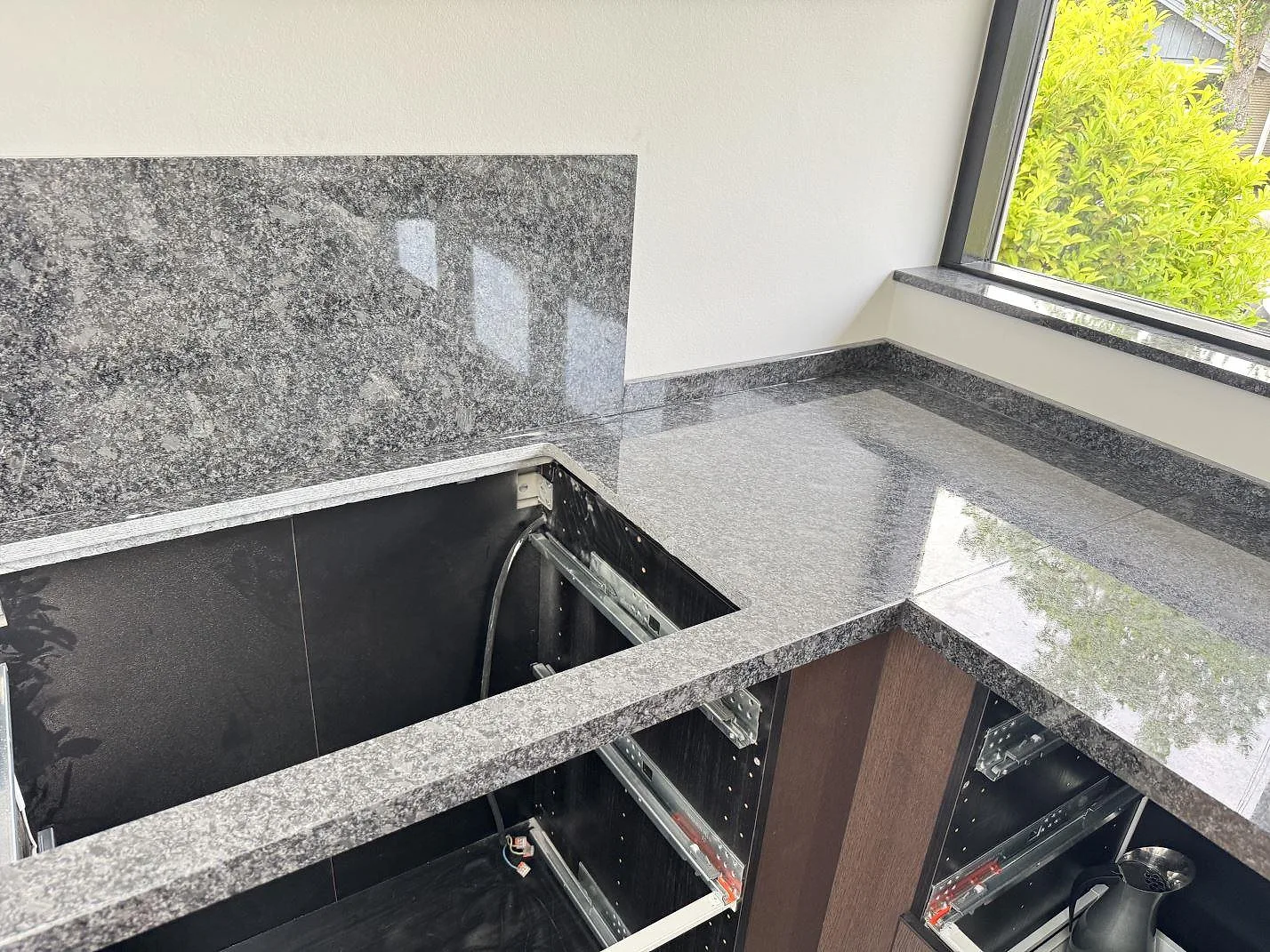 Köksbänkskiva i Steel Grey granit med öppet hällurtag, stänkskydd och fönsterbänk i samma sten i Tølløse.