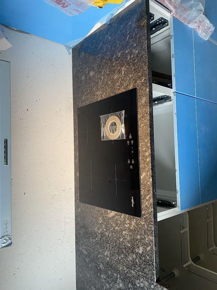 Polerad induktionshäll infälld i köksbänkskiva av Steel Grey granit i ett kök i Västra Frölunda.