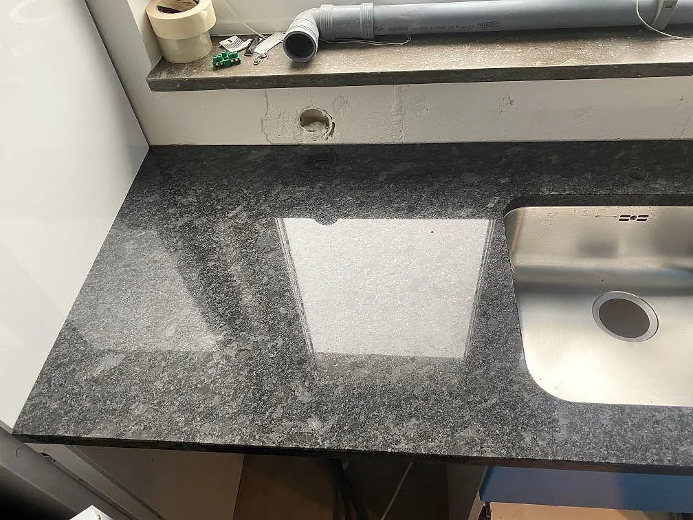 Närbild på den gråspräckliga ådringen i en polerad Steel Grey granitbänkskiva med urtag i ett kök i Västra Frölunda.