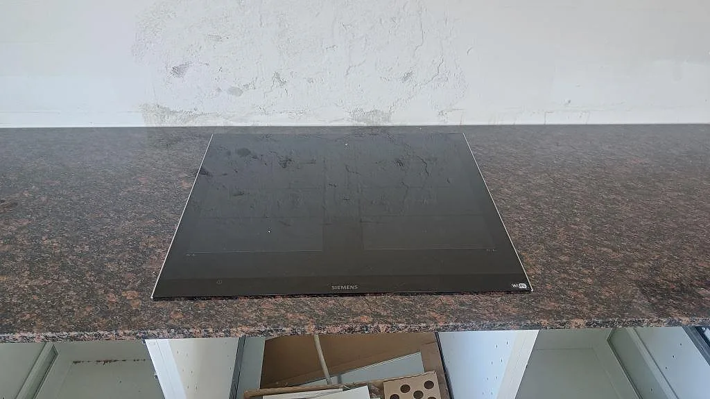 Svart induktionshäll infälld i polerad Tan Brown granitbänkskiva med mörk brun kornbild i Kastrup.