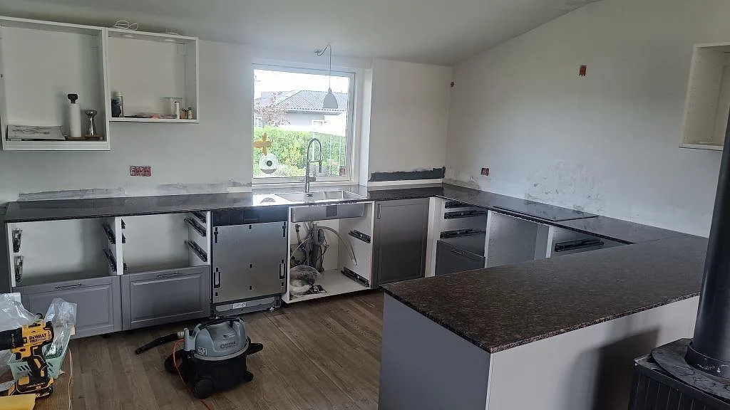 Köksbänkskiva i 20 mm polerad Tan Brown granit med halvö, diskzon vid fönster och ljusa köksstommar i Kastrup.