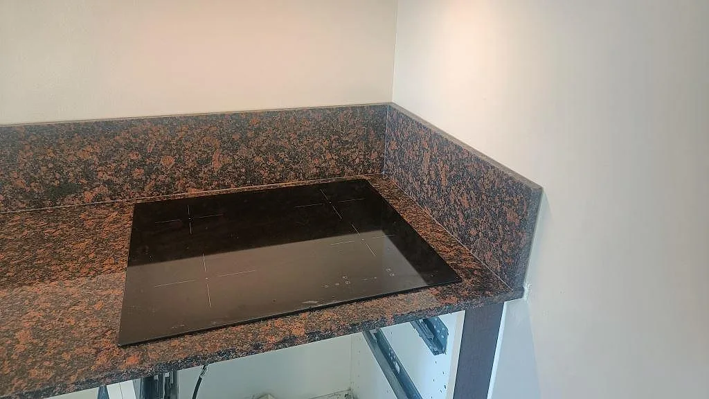 Häll placerad i polerad Tan Brown granit med matchande stänkkant vid köksväggen i Malmö.