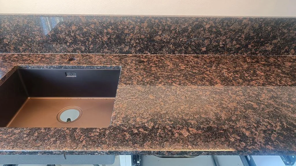 Polerad köksbänkskiva i Tan Brown granit med underlimmad diskho och uppvikt stänkkant i Malmö.