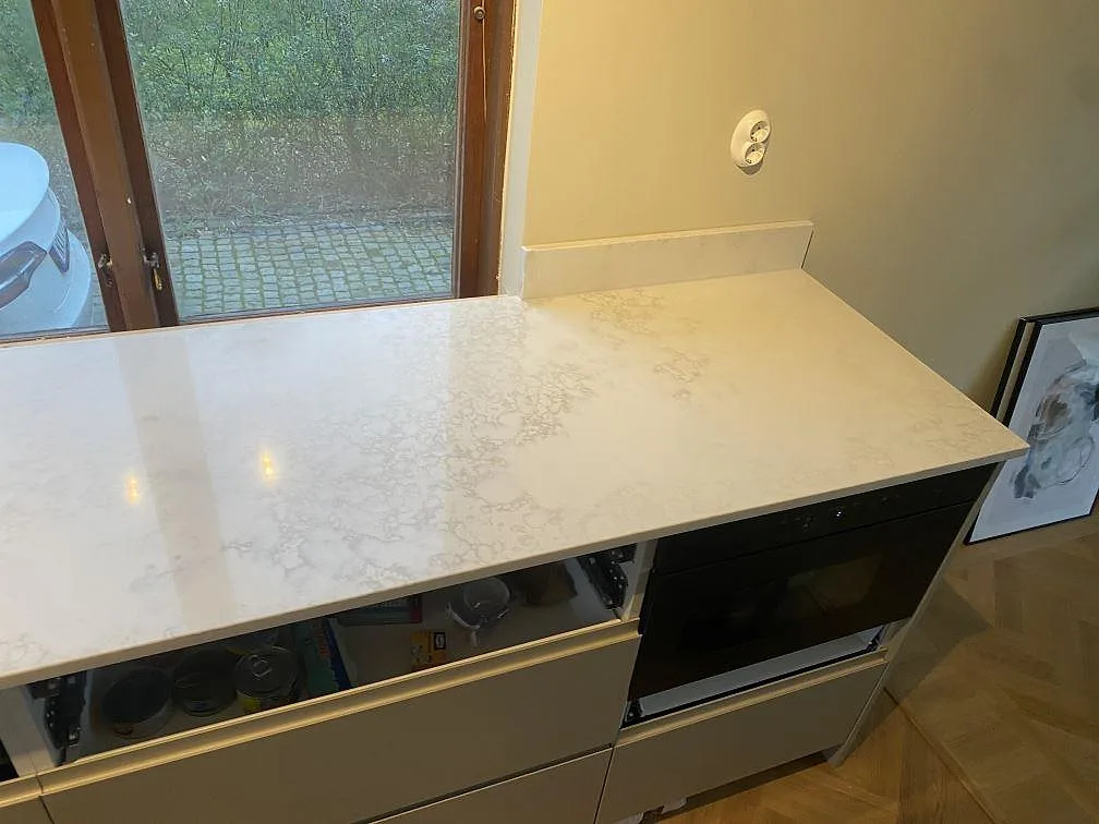 Köksbänkskiva i polerad Technistone Altamonte, komposit, på höger arbetsyta med låg stänkkant i Landskrona.