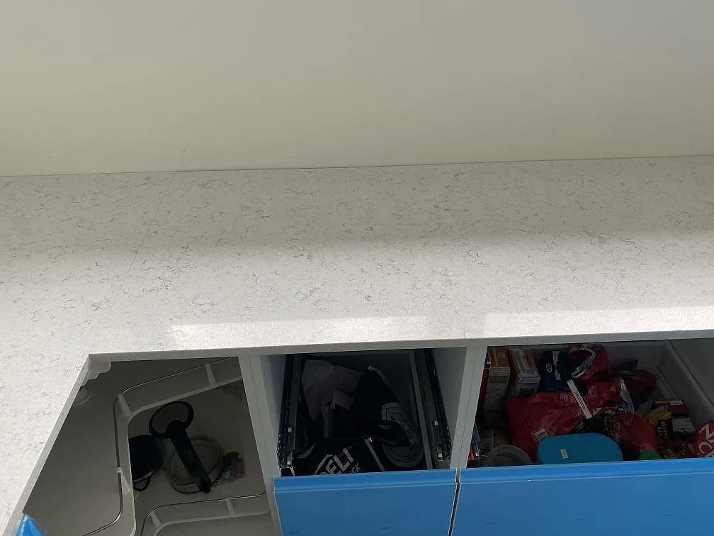 Köksbänkskiva i Technistone Brilliant Arabesco, vit kvartskomposit med grå ådring och polerad yta, i ett kök under montering i Vallberga.