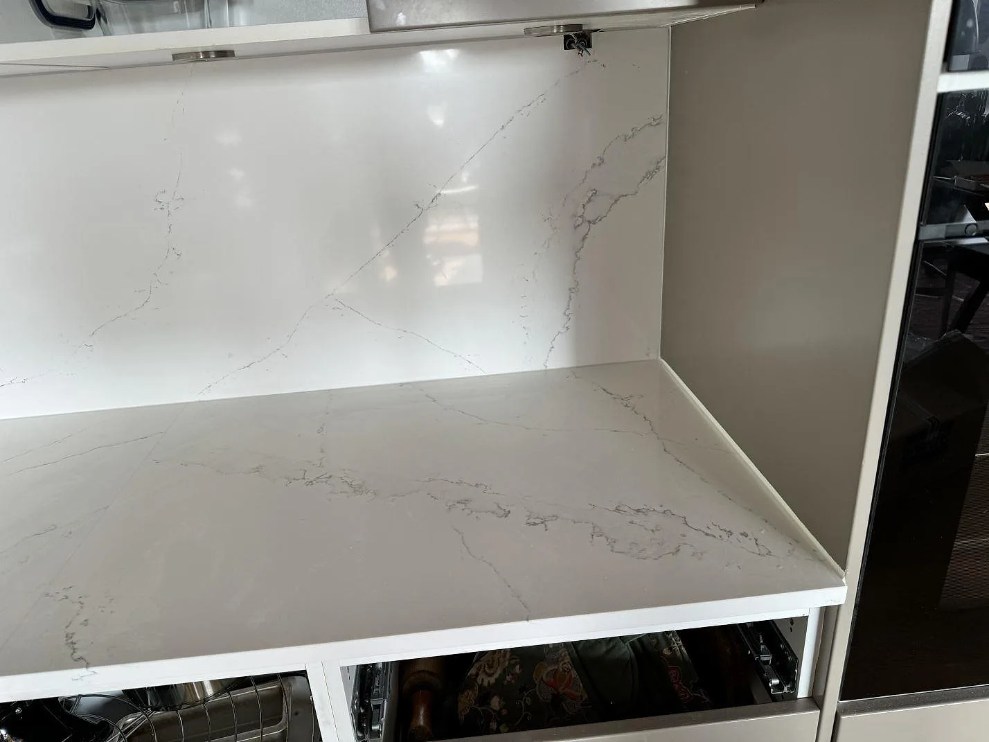 Köksbänkskiva i vit Technistone Calacatta Serchio, polerad kvartskomposit, med matchande stänkskydd och öppna stommar i Malmö.