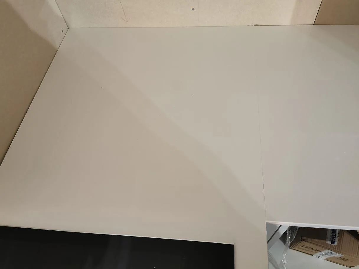 Vinkelmonterad köksbänkskiva i polerad vit Technistone Crystal Absolute White med induktionshäll i ett kök i Båstad.