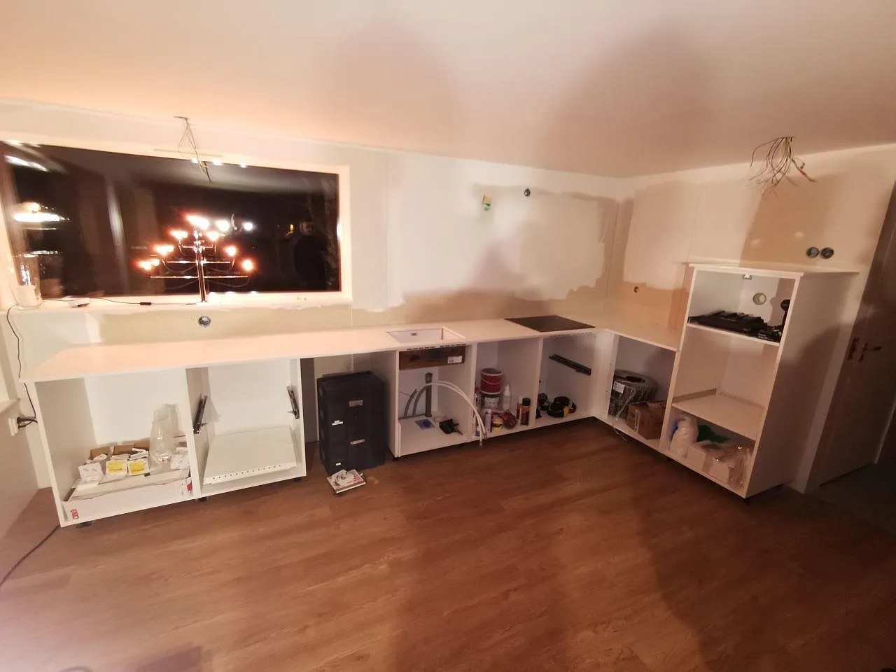 Köksbänkskiva i vit Technistone Crystal Absolute White, polerad, monterad längs väggen i ett vinkelkök under montering i Båstad.