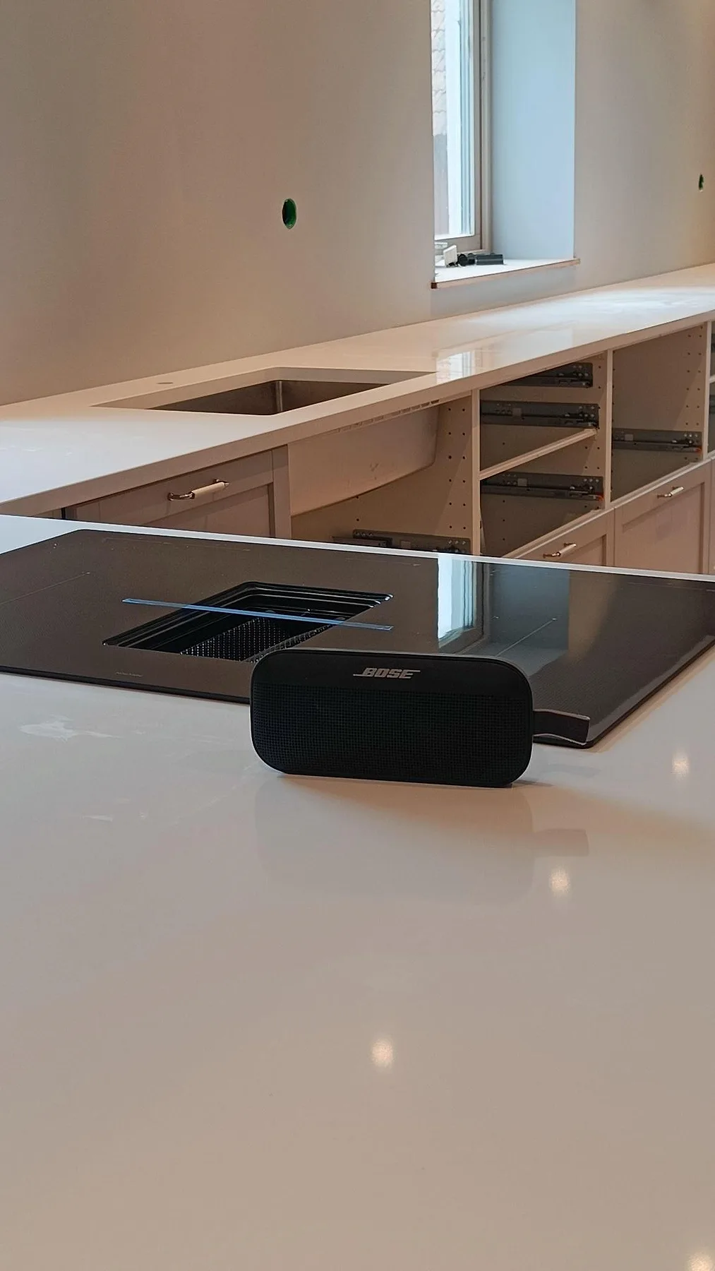 Närbild på polerad vit köksbänkskiva i Technistone Crystal Absolute White med svart häll framför diskzonen i Fjälkinge.
