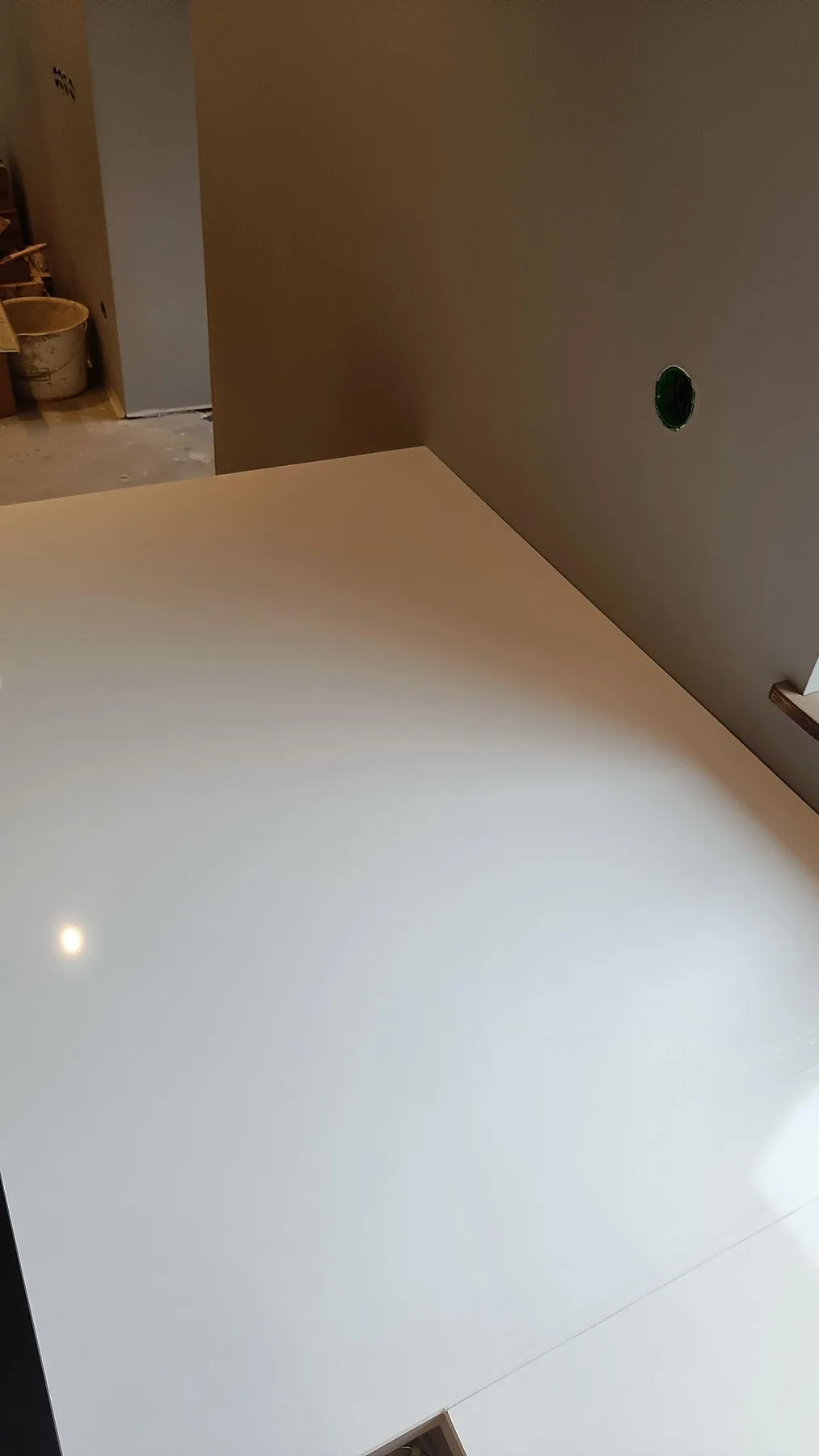 Hörndetalj av polerad köksbänkskiva i Technistone Crystal Absolute White mot vägg under montering i Fjälkinge.