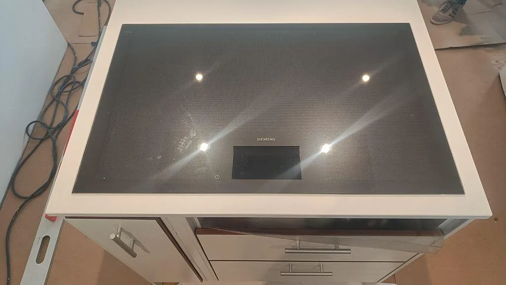 Detalj av svart häll infälld i vit Technistone Crystal Absolute White, polerad komposit på köksö i Glumslöv.