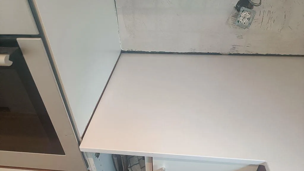 Rak väggbänkskiva i Technistone Crystal Absolute White, polerad vit komposit, under montering i kök i Glumslöv.