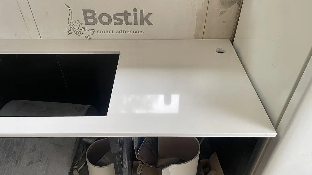 Närbild på vit polerad kompositbänkskiva i Härryda med rektangulär hällöppning och blank yta.