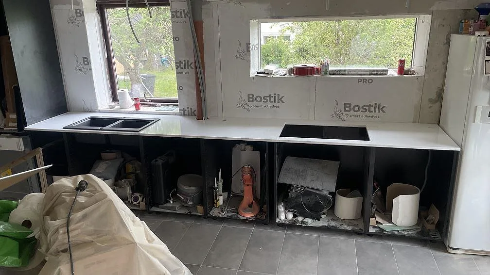 Köksbänkskiva i polerad Technistone Crystal Absolute White, vit kvartskomposit, monterad längs fönsterväggen i ett kök i Härryda.