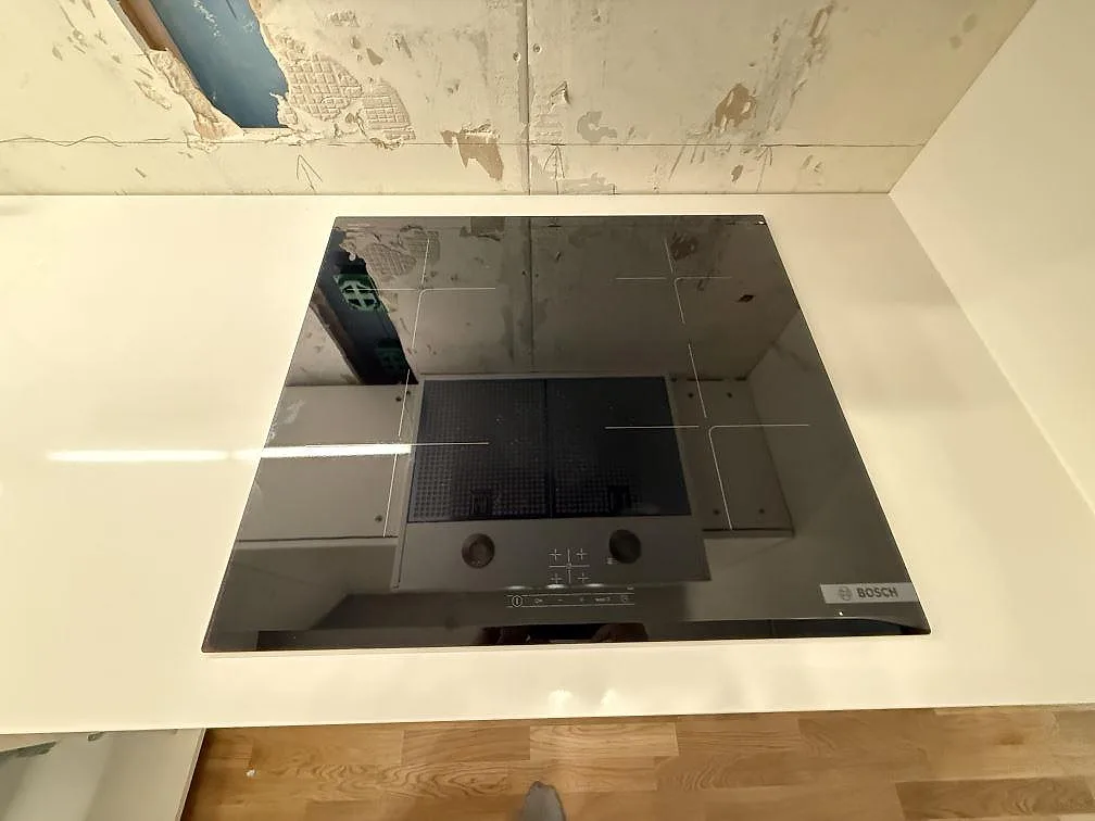 Närbild av svart häll i polerad Technistone Crystal Absolute White, vit kvartskompositbänkskiva i kök i Kungsängen.