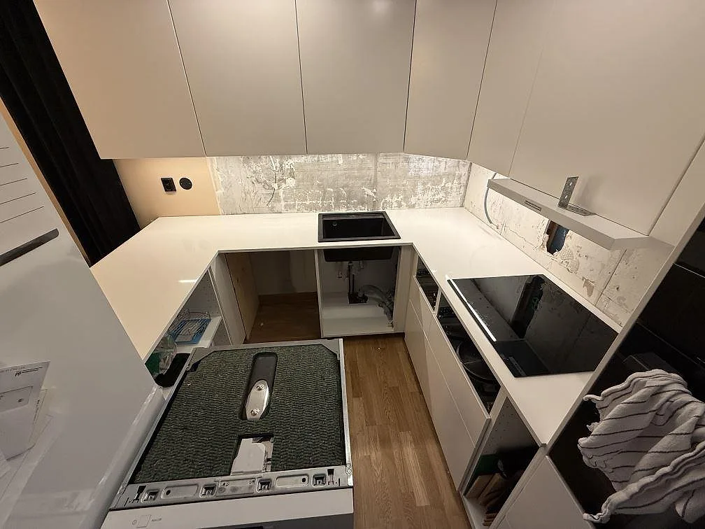 Översikt av kök i Kungsängen med 20 mm polerad Technistone Crystal Absolute White som bänkskiva runt diskho, häll och hörn.