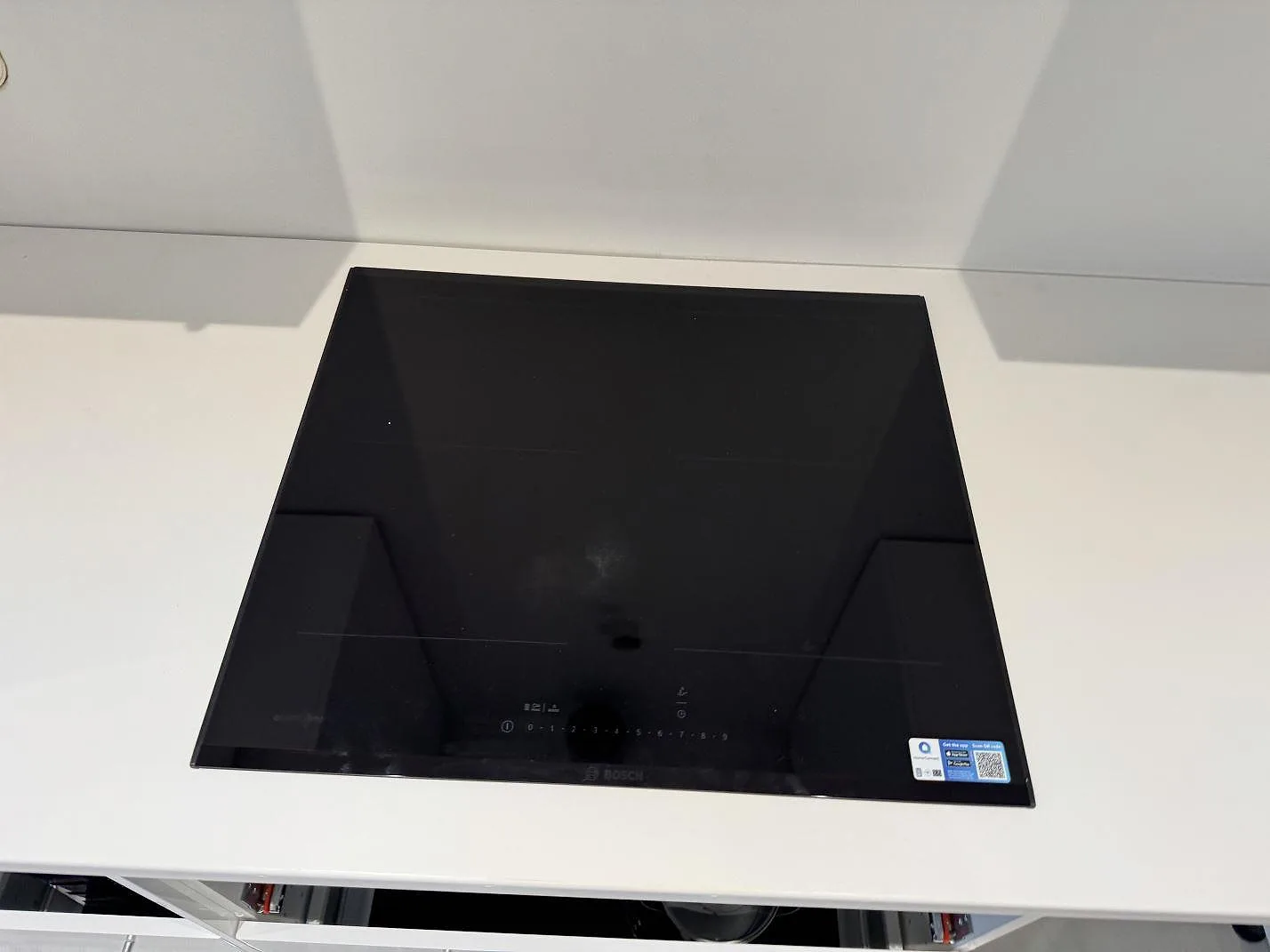 Närbild av svart häll monterad i en polerad vit Technistone Crystal Absolute White köksbänkskiva i Trelleborg.