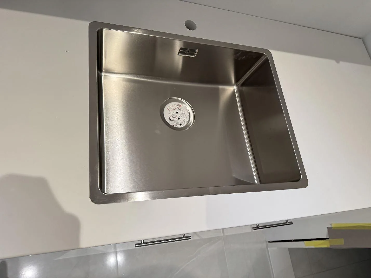 Närbild av rostfri diskho i en polerad vit Technistone Crystal Absolute White bänkskiva i kök i Trelleborg.