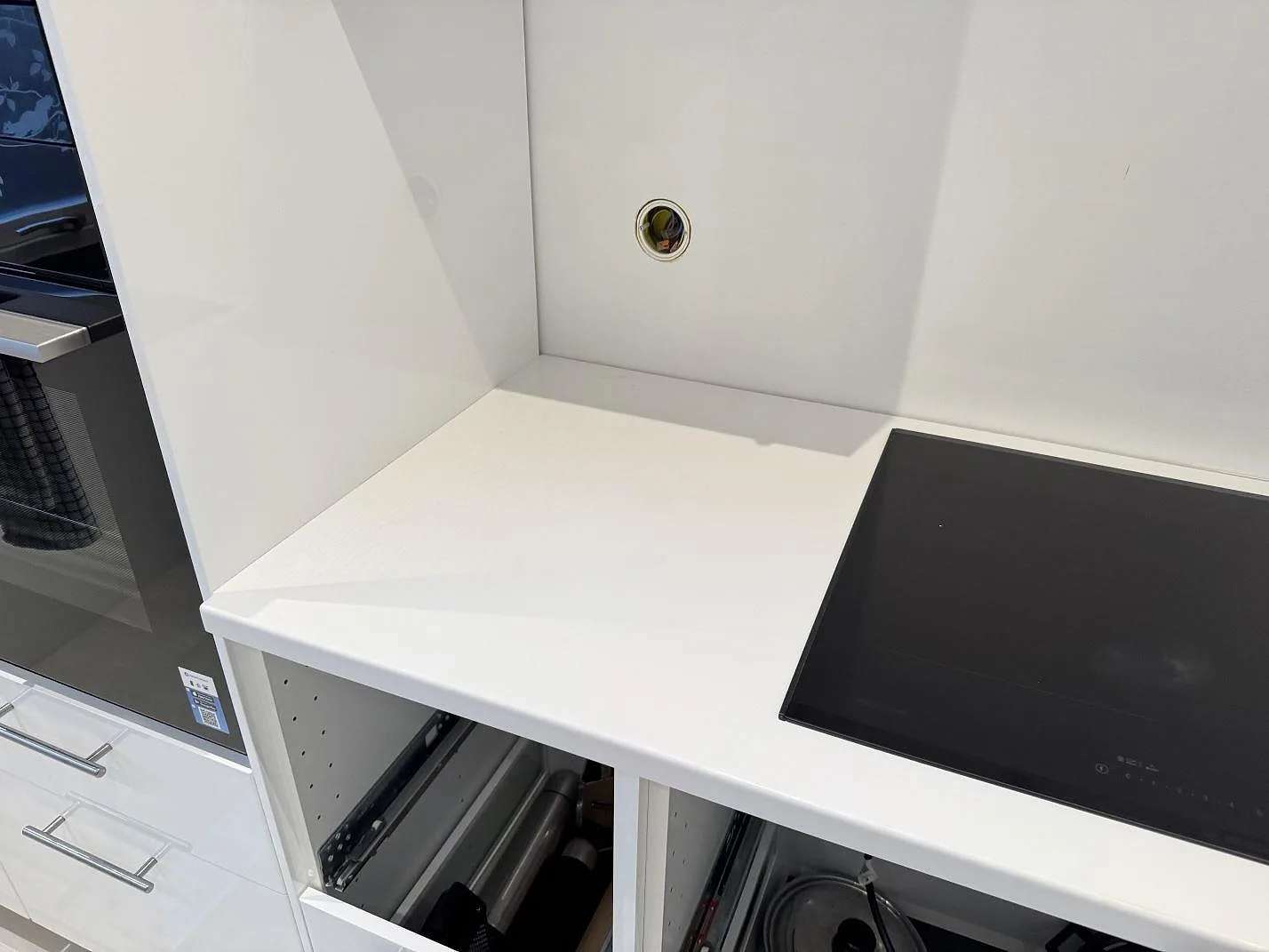 Vit polerad kompositbänkskiva i Technistone Crystal Absolute White med svart häll och ugnssektion under montering i Trelleborg.
