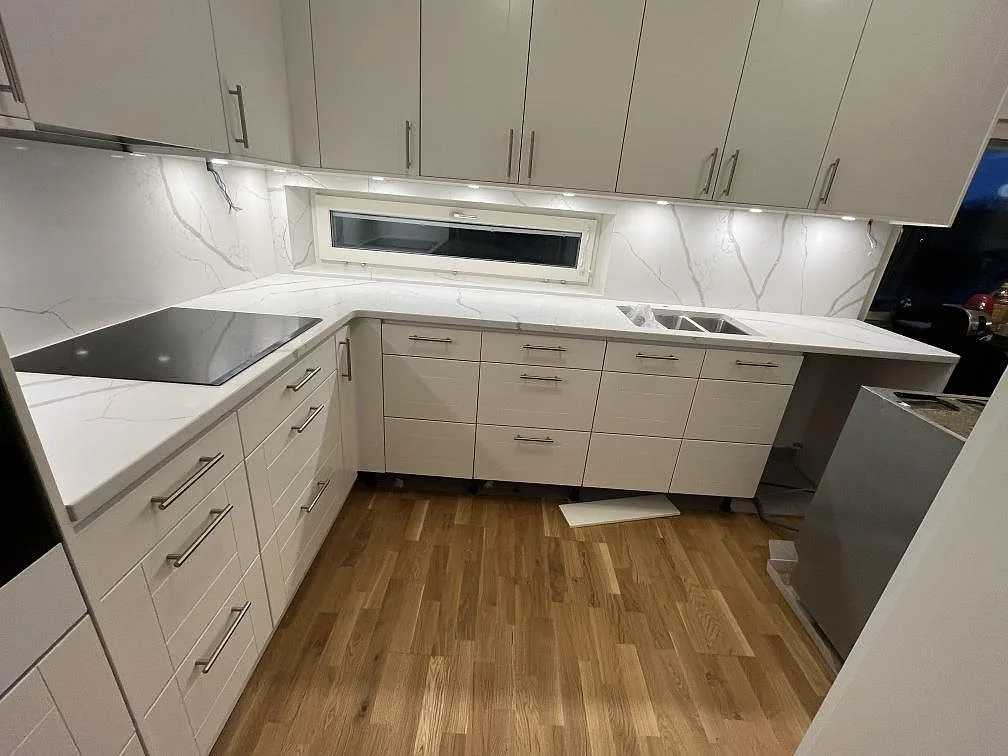 Köksbänkskiva i vit Technistone Crystal Calacatta Silva, polerad komposit, med U-format kök, induktionshäll och stänkskydd i Kungsholmen, Stockholm.