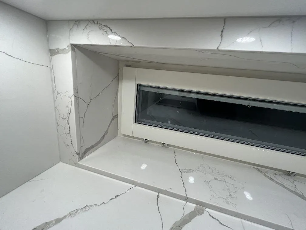 Stenklädd fönsternisch i Technistone Crystal Calacatta Silva med polerad yta och grå ådring över bänkskivan i Kungsholmen, Stockholm.