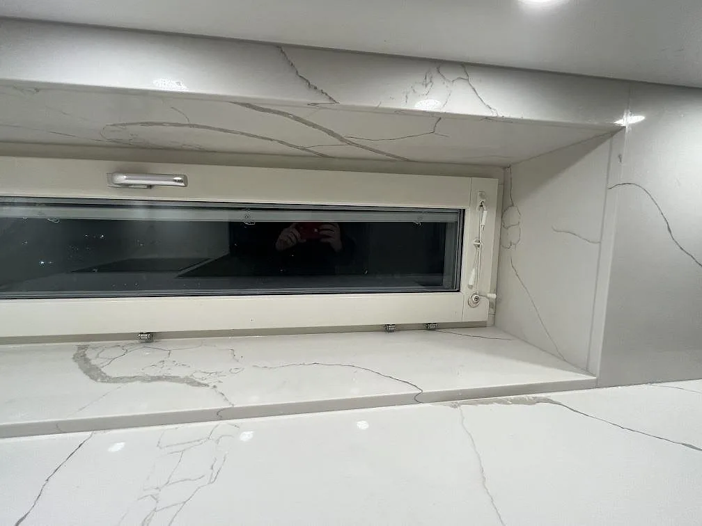 Detalj av polerad Technistone Crystal Calacatta Silva runt fönsternisch och stänkskydd i kök i Kungsholmen, Stockholm.