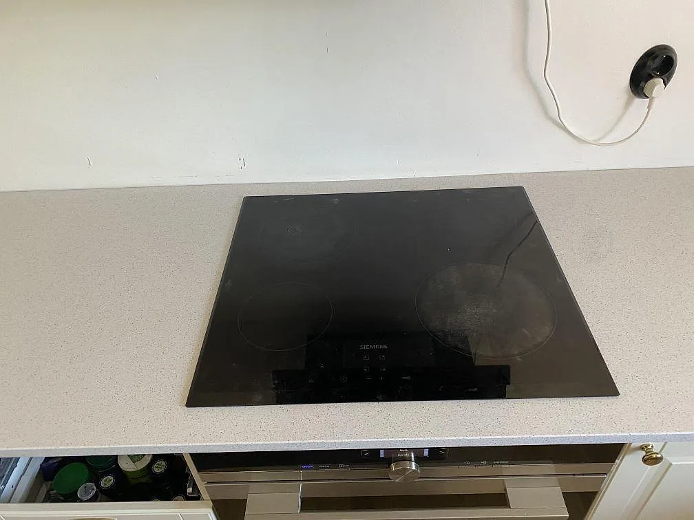 Infälld Siemens induktionshäll i en vit polerad köksbänkskiva av Technistone Crystal Quartz White i ett kök i Malmö.