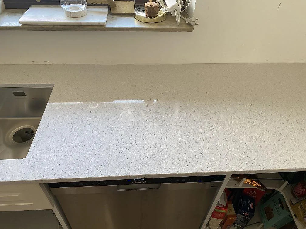 Vit polerad köksbänkskiva i Technistone Crystal Quartz White med underlimmad rostfri diskho och Siemens diskmaskin i ett kök i Malmö.