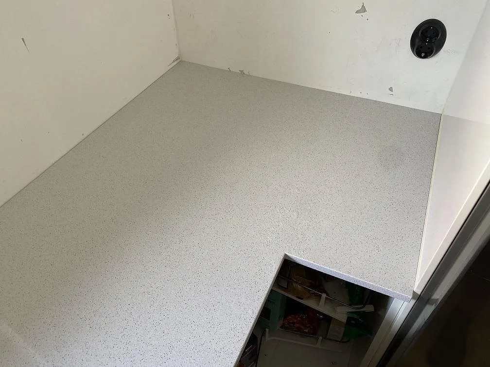 Vit polerad köksyta i Technistone Crystal Quartz White installerad mot vägg under montering i ett kök i Malmö.