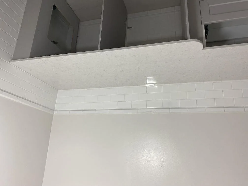 Detalj av polerad Technistone Glencoe som bänkskiva och stänkkant mot vitt kakel i Ängelholm.