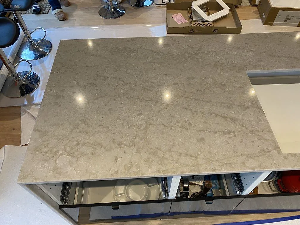 Närbild av polerad Technistone Glencoe på köksö med öppet urtag och blank kvartskomposit i Alafors.