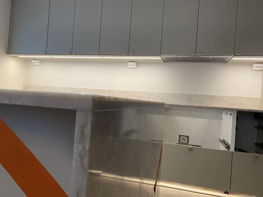 Sidovy av köksö i polerad Technistone Glencoe med väggbänk och låg stänkkant bakom i ett kök i Bunkeflostrand.
