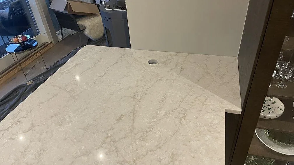 Detalj av polerad Technistone Glencoe vid vägganslutning, med rundat innerhörn och runt urtag i Landvetter.