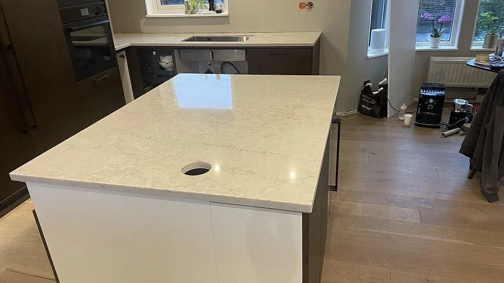 Köksö i polerad Technistone Glencoe med runt urtag och bakre bänkskiva i ett kök i Landvetter.