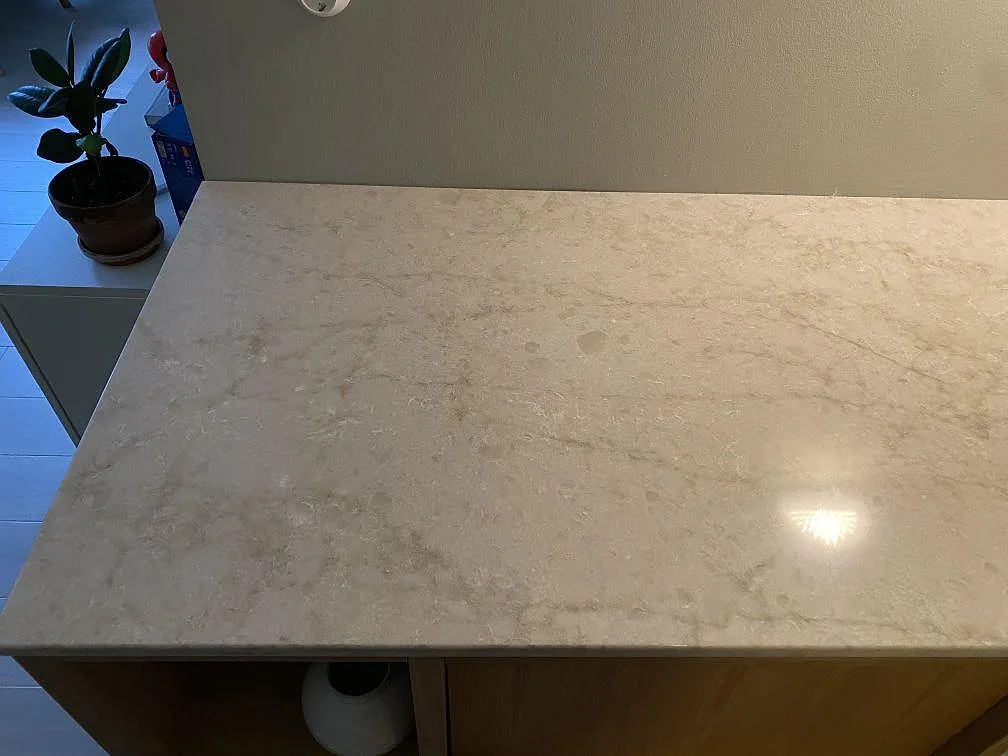 Detalj av polerad Technistone Glencoe som ljus köksbänkskiva med mjuk stenlik teckning och vägganslutning i Malmö.
