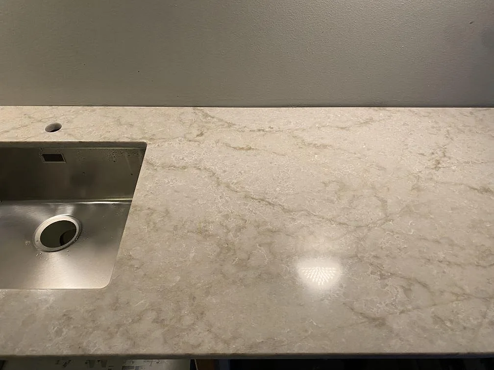 Polerad köksbänkskiva i Technistone Glencoe med rostfri diskho, blandarhål och tydlig gråbeige ådring i Malmö.