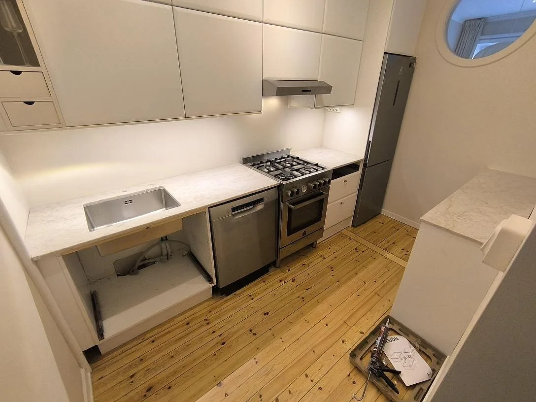Köksbänkskiva i Technistone Glencoe komposit, polerad, i ett kompakt kök med diskho, fristående spis och sidobänk i Stockholm.