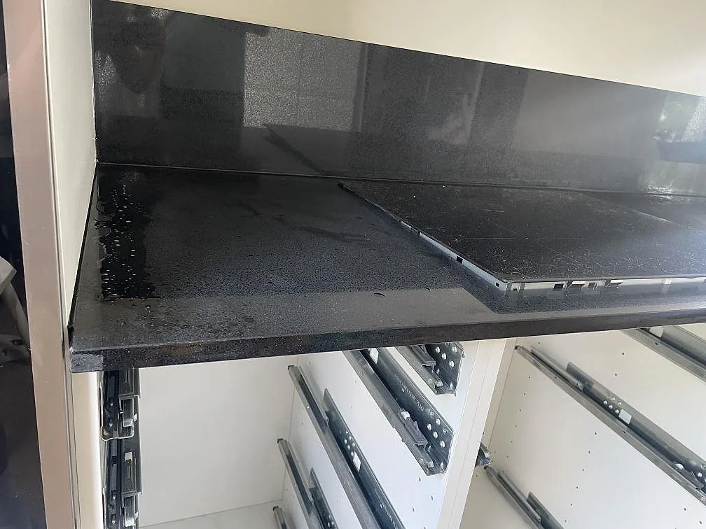 Detalj av polerad Technistone Gobi Black bänkskiva med stänkskydd och hällzon i ett kök i Borås.