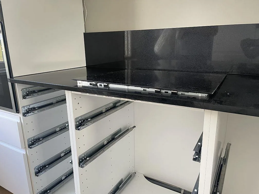 Köksbänkskiva och stänkskydd i polerad Technistone Gobi Black med hälluttag över vita stommar i Borås.