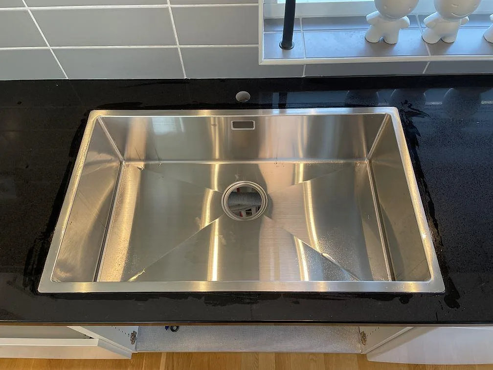 Rostfri diskho monterad i polerad Technistone Gobi Black komposit med mörk sten runt diskhon i Dalby.