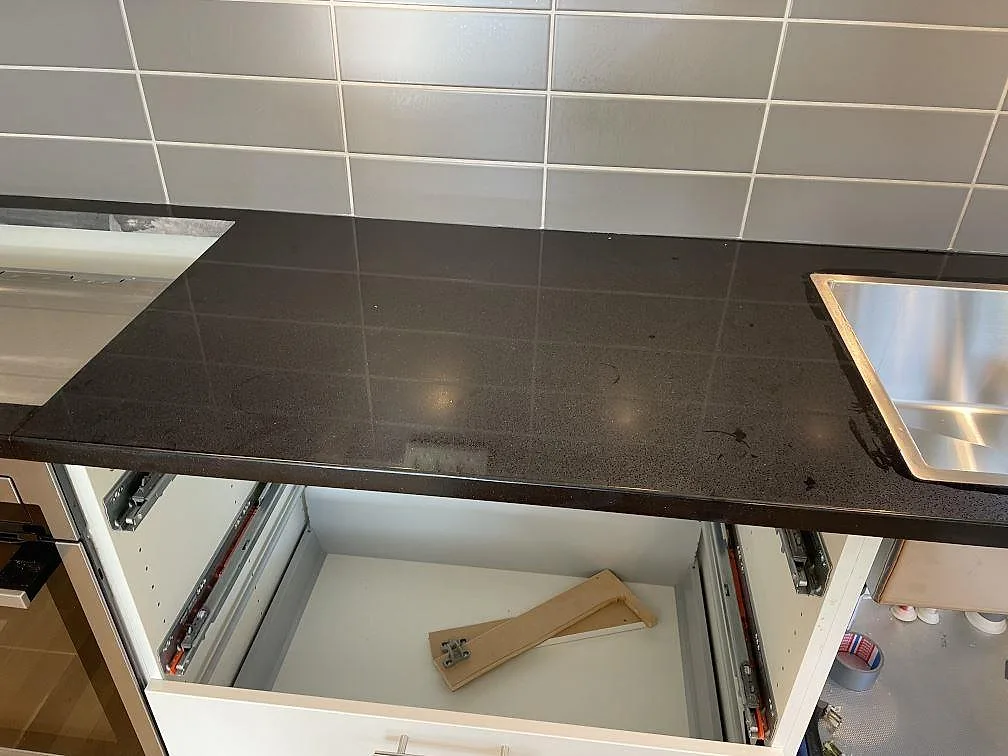 Rak bänkyta i polerad Technistone Gobi Black komposit mellan diskho och hällzon i kök i Dalby.
