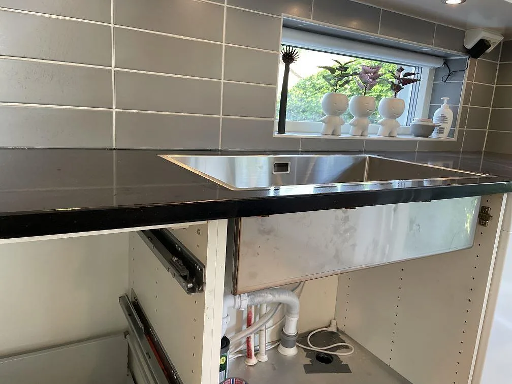 Köksbänkskiva i polerad Technistone Gobi Black komposit med rostfri diskho och grå kakelvägg i Dalby.