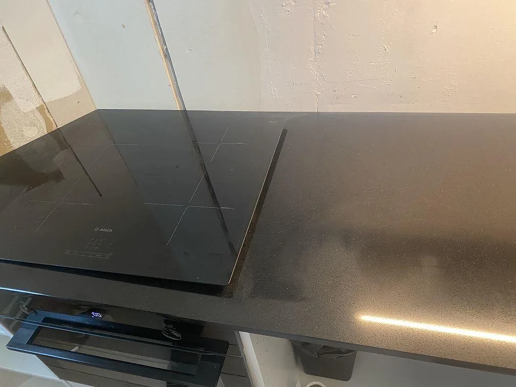 Svart köksbänkskiva i Technistone Gobi Black med induktionshäll och fin prickstruktur i ett kök i Göteborg.