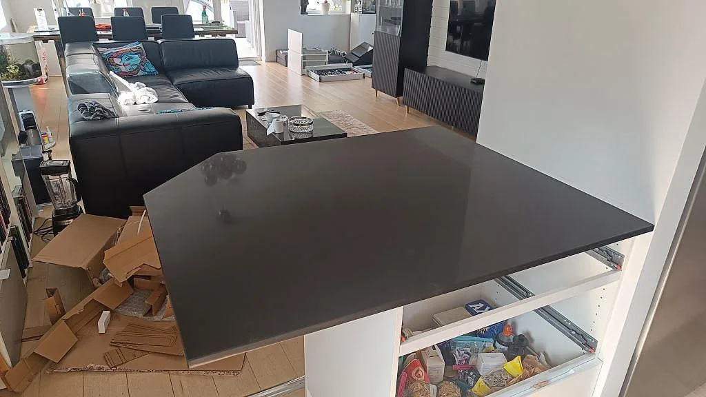 Större arbetsyta i svart Technistone Gobi Black, 20 mm polerad kvartskomposit, ut mot vardagsrummet i ett kök i Göteborg.