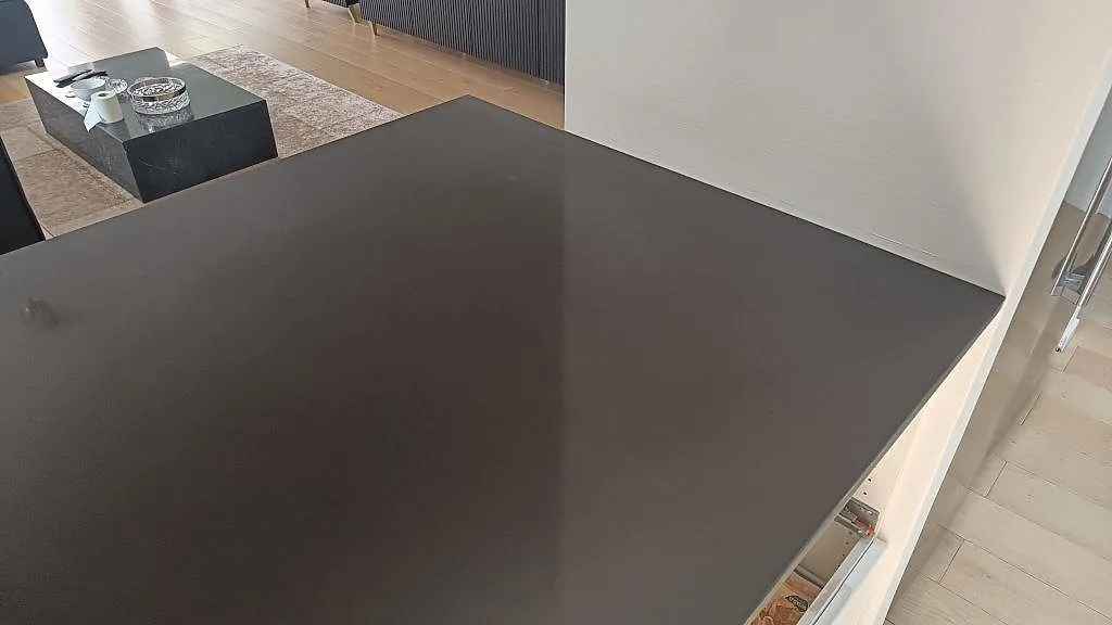 Närbild på den polerade arbetsytan i svart Technistone Gobi Black kvartskomposit vid vägg i köket i Göteborg.