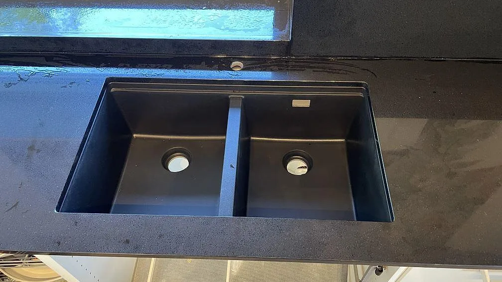 Närbild på svart dubbelho i polerad Technistone Gobi Black köksbänkskiva med fin kornbild i Kalmar.