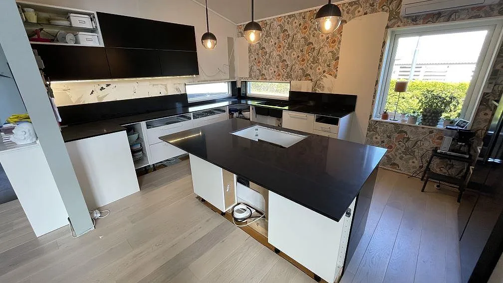 Köksbänkskiva i svart Technistone Gobi Black, 20 mm polerad kvartskomposit, med köksö och väggbänkar i ett kök i Kalmar.