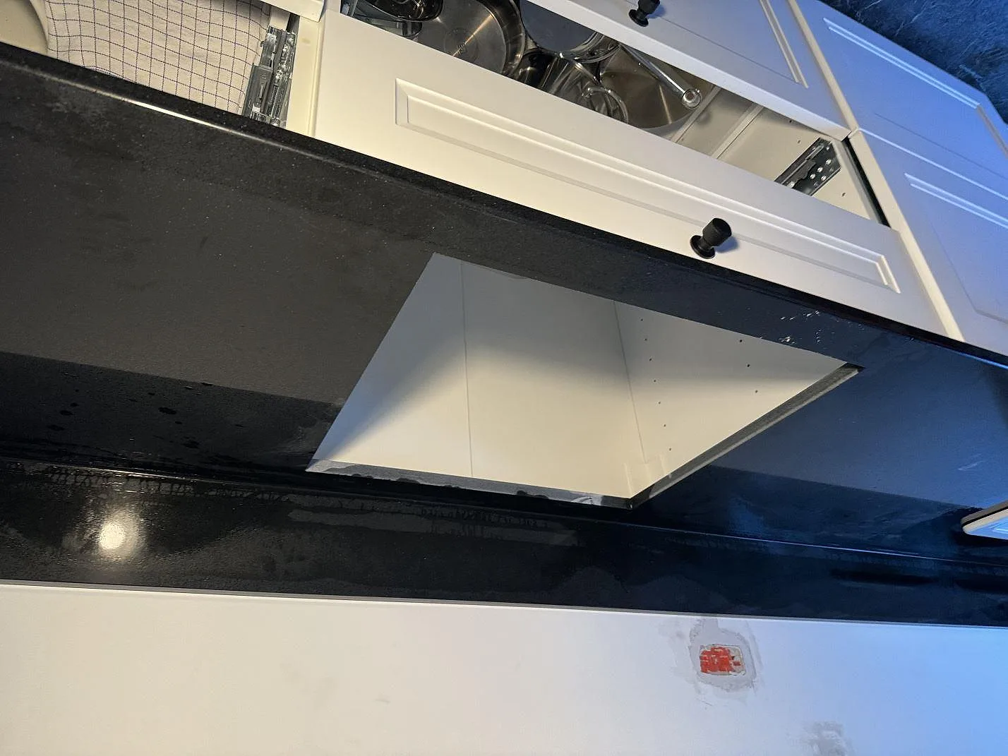 Svart polerad kompositbänkskiva i Technistone Gobi Black med utskärning för häll under montering i Kastrup.
