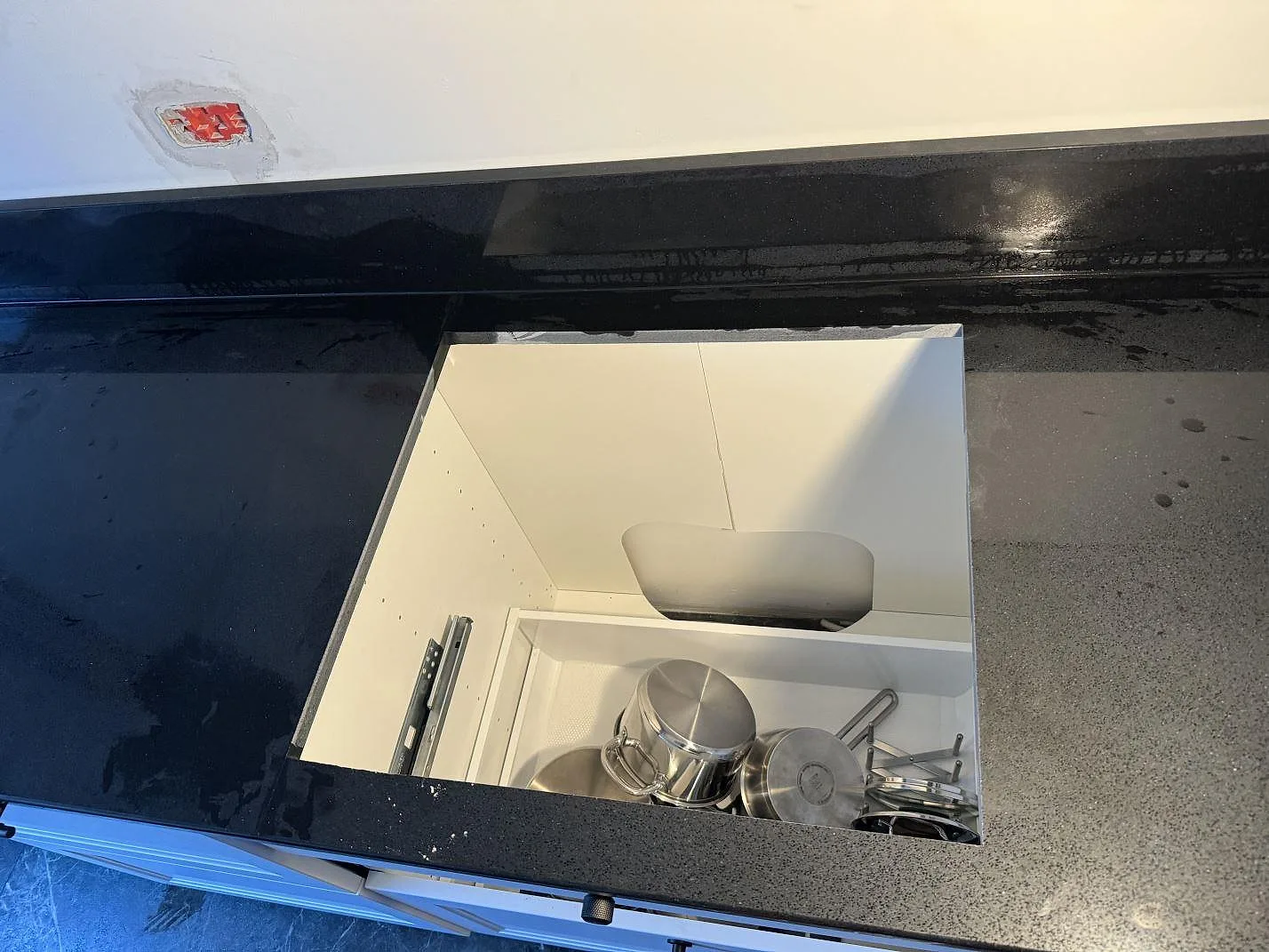 Hällöppning i polerad svart Technistone Gobi Black kompositbänkskiva med vit köksinredning i Kastrup.