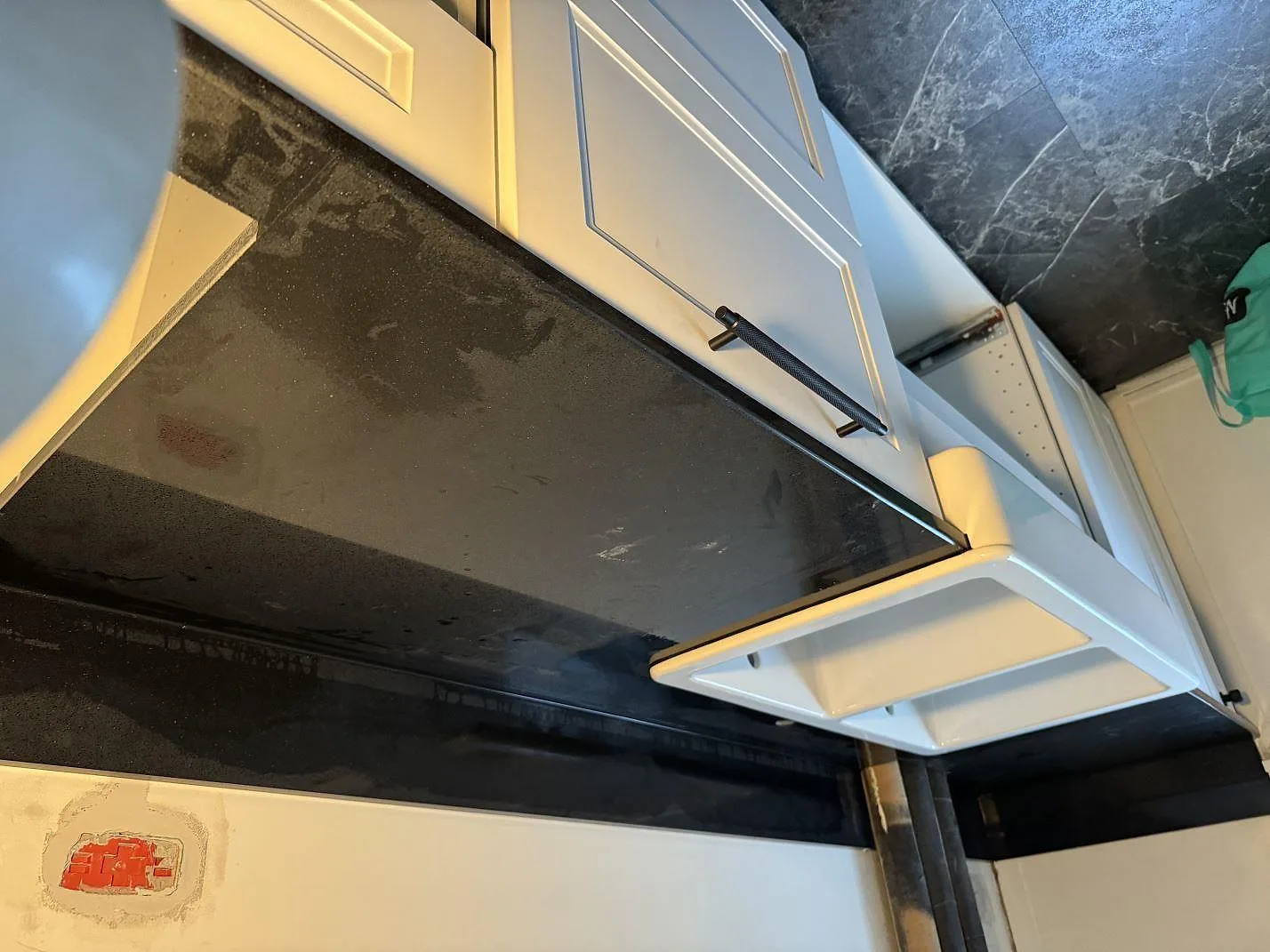 Lång köksbänkskiva i polerad Technistone Gobi Black komposit mot vita shakerluckor i Kastrup.